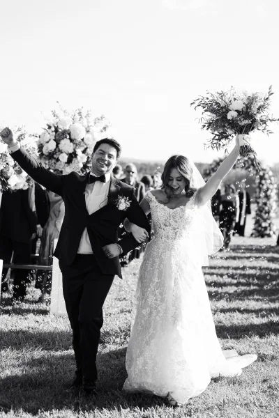Ceremony exit as newlyweds stride through a bubble wedding exit, hand in hand, bride lifting her bouquet amid cheering guests beneath a floral arch.