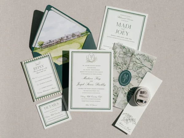 Invitation suite wedding invitation set flat lay with envelope, venue card, RSVP and details cards, monogram seal, rings on linen