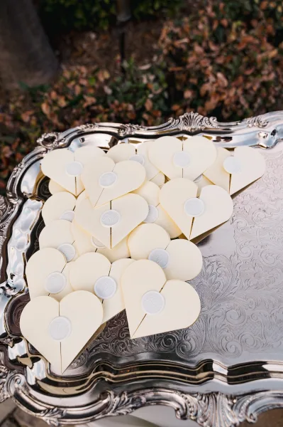 Wedding favor boxes with heart favor boxes, monogram wax seals on a silver serving tray set among outdoor foliage and fallen leaves