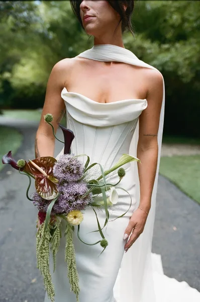 Bridal portrait of a bride holding bouquet, highlighting a sculptural calla lily arrangement with graceful, flowing lines.