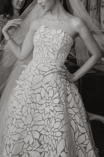 Wedding dress close-up of a floral applique wedding dress with 3D blossoms, the veil framing a strapless, textured bodice.