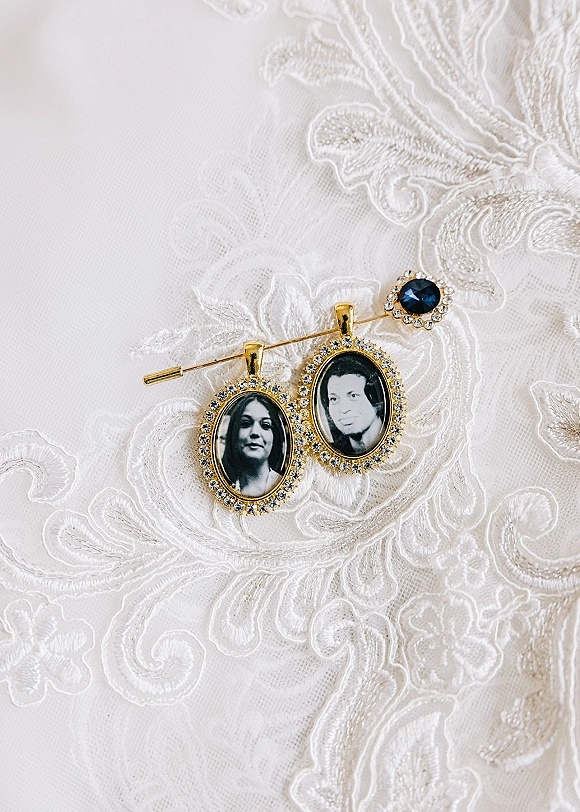 Wedding photo locket bridal heirloom jewelry brooch with crystal halo and blue gemstone resting on ivory lace fabric background