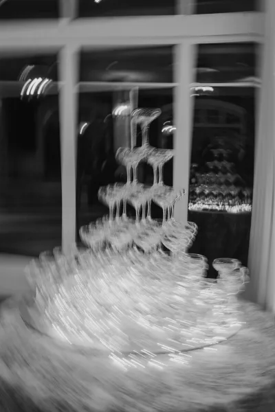 Champagne tower wedding champagne tower of stacked coupes with bubbling pour, set by window panes in an indoor reception space