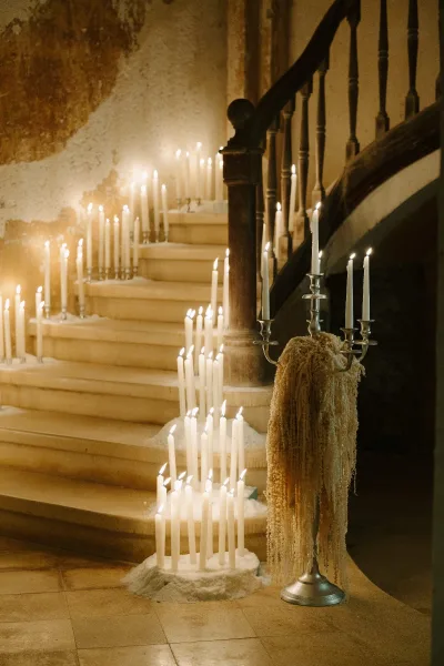 Candlelit wedding staircase with wedding staircase candles in silver candelabras and taper candles, wax drips along wooden banister steps