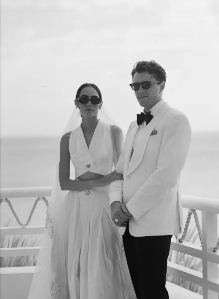 Couple portrait captured as a black and white wedding portrait on a balcony above the ocean, the bride’s veil framed against the horizon.
