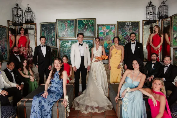 Wedding party portrait of a colorful bridal party, the bride holding an orange bouquet, with decorative birdcages in the background.