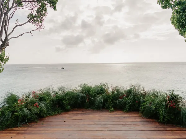 Ceremony setup on a wooden platform facing an oceanfront ceremony backdrop, with open sky and clouds along the distant horizon.