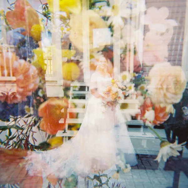 Bridal portrait of a bride with bouquet on porch steps outside a house, pausing in a quiet moment that highlights her graceful poise.