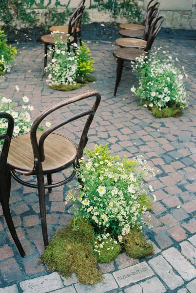 Ceremony aisle design for outdoor ceremony seating, lined with bentwood chairs on cobblestone paving against an ivy wall backdrop.