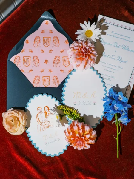 Wedding invitation suite with scalloped edge invitations and a patterned liner arranged neatly on red velvet fabric