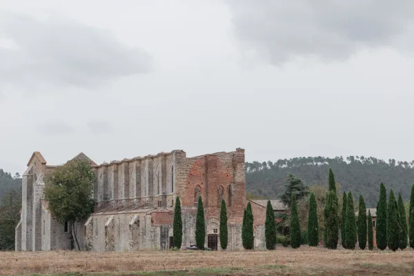 Wedding venue exterior of a historic wedding venue with stone arches and wooden doors, framed by cypress trees under a cloudy sky