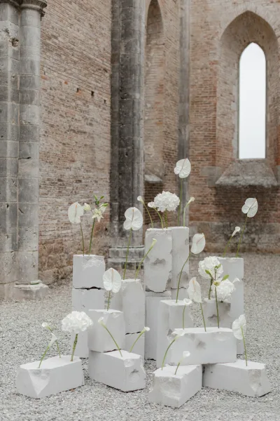 Wedding floral installation of modern wedding flowers on white stone blocks with anthurium and hydrangea against brick walls and arches