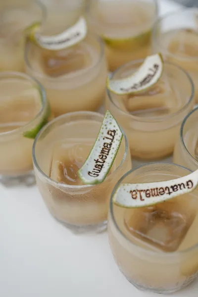 Signature cocktails on a white table, clear drinks in rocks glasses with ice cubes and lime wedges on personalized cocktail picks