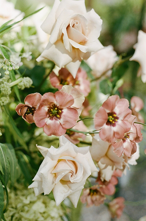 Wedding flowers in a white rose bouquet with blush blooms and greenery accents, styled in an airy arrangement against soft garden foliage