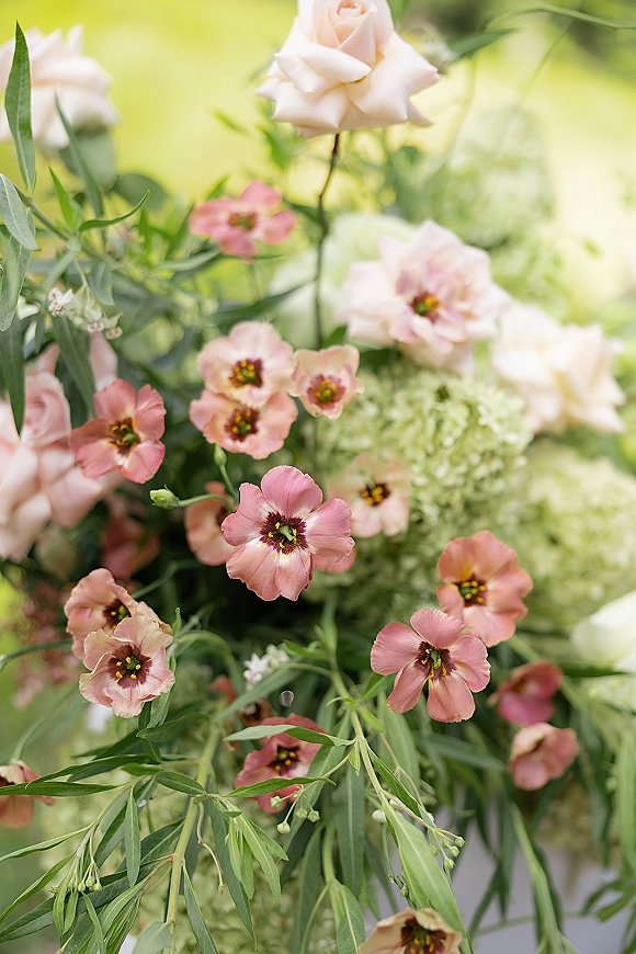 Wedding flowers with blush rose wedding flowers in soft pink blooms and green foliage, resting on a green lawn background