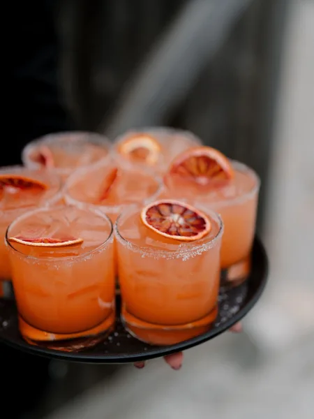 Signature cocktail during tray passed cocktails, a vibrant drink in a clear glass crowned with a striking blood orange garnish.