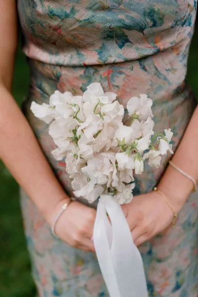 Bouquet close-up of a sweet pea wedding bouquet, hand-tied with a trailing ribbon, delicate white blooms gathered in a petite, organic posy.