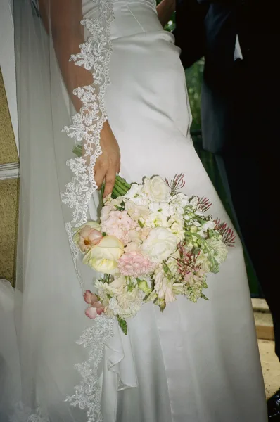 Bridal bouquet, an ivory and blush bouquet with roses and soft greenery, held close against a simple bridal gown for a romantic look.
