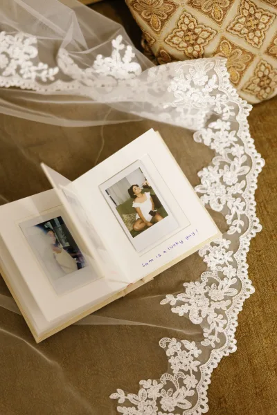Polaroid guest book open as an instant photo guest book, showing prints and a heartfelt handwritten note on a brown upholstered sofa.