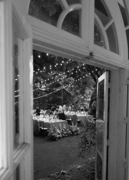 Outdoor reception decor with garden reception lighting as string lights glow above long tables beneath garden trees in a cozy courtyard.