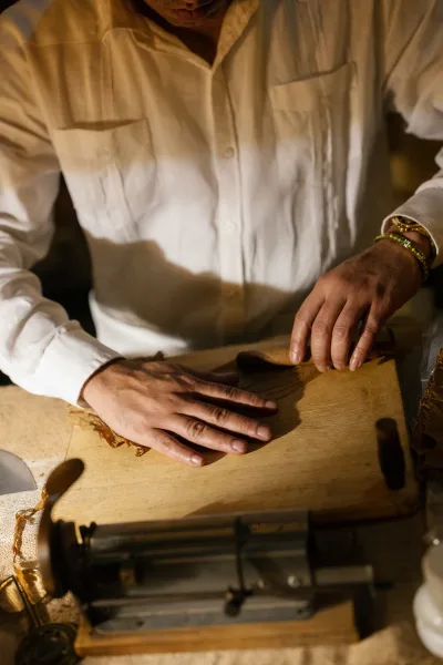Cigar rolling station at a wedding cigar bar, tobacco leaves spread across a wooden table draped with burlap.