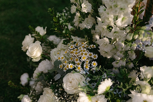 Wedding florals with white wedding flowers, featuring white roses and chamomile daisies with eucalyptus greenery on a garden lawn
