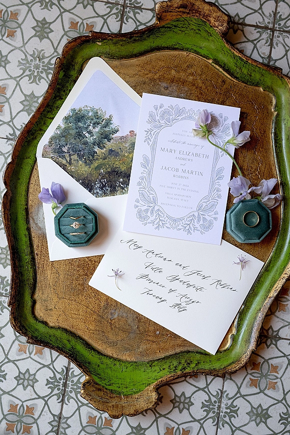 Invitation suite wedding invitation set arranged with ring boxes, engagement ring, lilac flowers and cards on a patterned tile floor