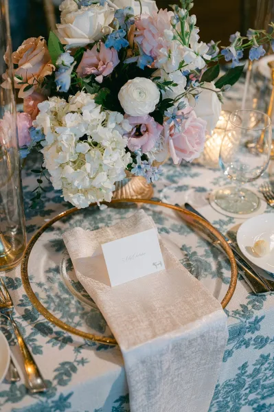 Reception tablescape featuring an elegant wedding place setting with a floral centerpiece on a patterned tablecloth