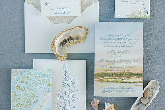 Invitation suite with a watercolor wedding invitation, calligraphy envelopes and RSVP card, styled with oyster shell on gray linen fabric