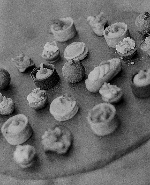 Wedding dessert bites arranged on a serving board with mini pastries, petit fours, and bite-size tarts topped with frosting and crumbs
