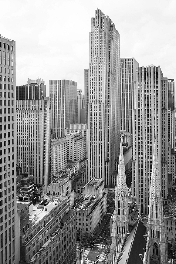 City skyline in black and white skyline tones, with dense downtown skyscrapers and gothic church spires under an overcast sky