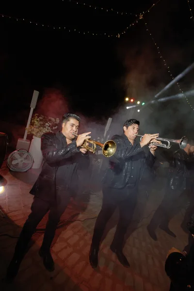 Wedding reception band performing live wedding music with gleaming trumpets under the night sky on patio pavers