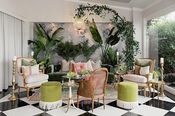 Wedding lounge area with reception lounge seating, velvet sofa and green ottomans around a glass coffee table on a checkered floor under a disco ball pendant light