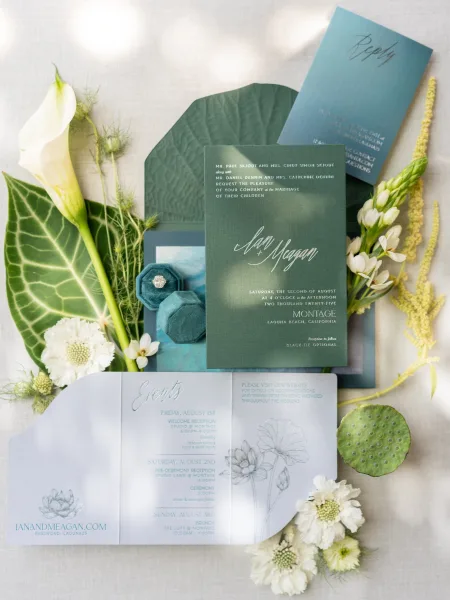 Invitation suite wedding invitation flat lay with RSVP and details cards, teal velvet ring box and ring, calla lily on linen backdrop