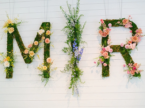 Floral monogram decor wedding monogram letters made of moss and pastel blooms, with roses and greenery sprays on a white shiplap wall