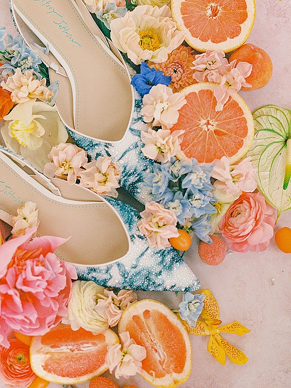 Bridal shoes, beaded wedding shoes in blue and white with pointed toes, styled with fresh flowers and grapefruit slices on a light surface