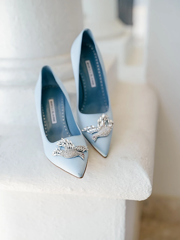 Bridal shoes in light blue wedding shoes style, pointed-toe heels with crystal bird clips displayed on white staircase steps