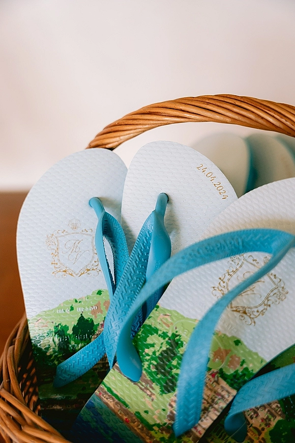 Wedding favor flip flops displayed in a wedding flip flop basket, personalized with monogram and date imprint on a tabletop by a white wall