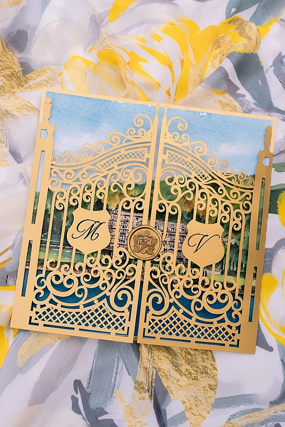 Wedding invitation with laser cut gatefold gold cardstock, monogram initials and wax seal, on patterned floral paper with leaf motif