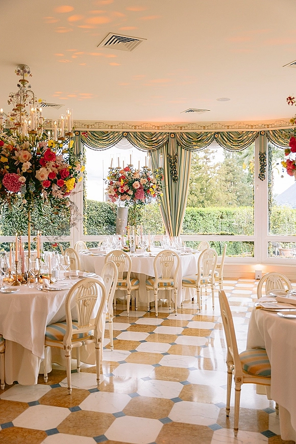 Reception tablescape with wedding reception decor featuring floral candelabra centerpieces, taper candles, and window wall garden views
