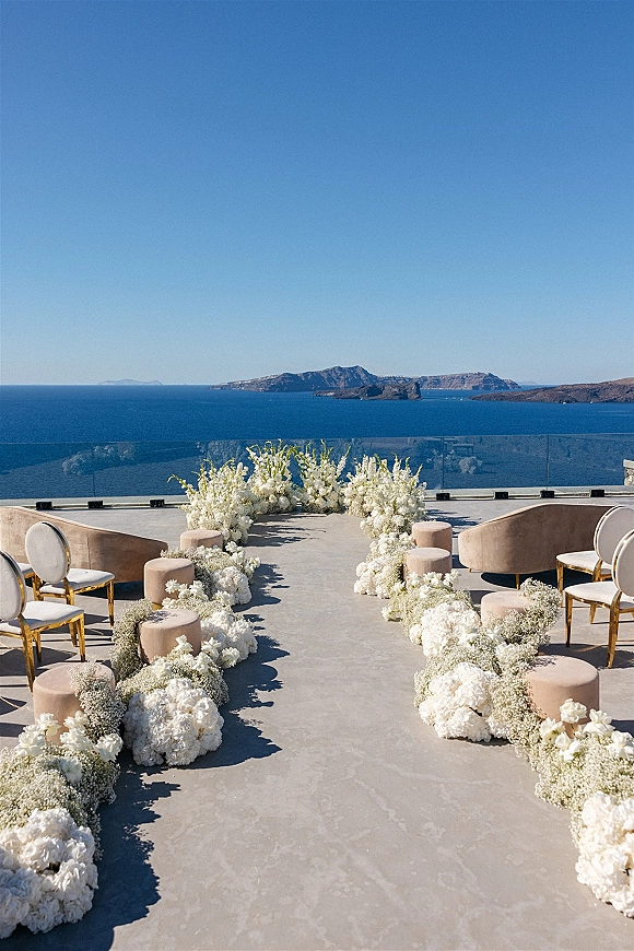Ceremony aisle decor with a floral aisle runner of white hydrangeas and baby’s breath on a terrace patio overlooking the ocean and islands