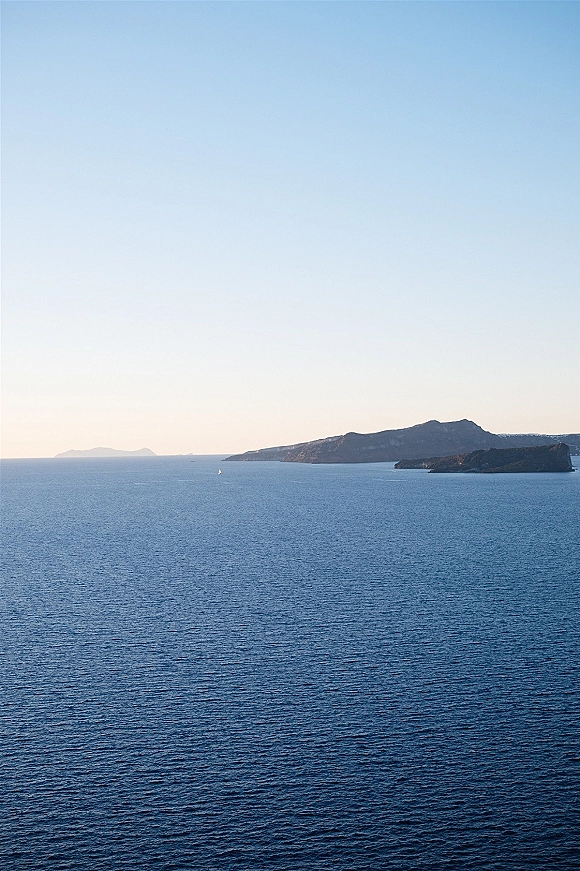 Ocean view wedding venue ocean view with a lone sailboat on calm blue sea, distant islands on the horizon under a clear sky