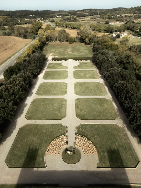 Outdoor ceremony setup with garden wedding ceremony layout, round chairs and floral aisle accents on a formal lawn with hedges and gravel paths