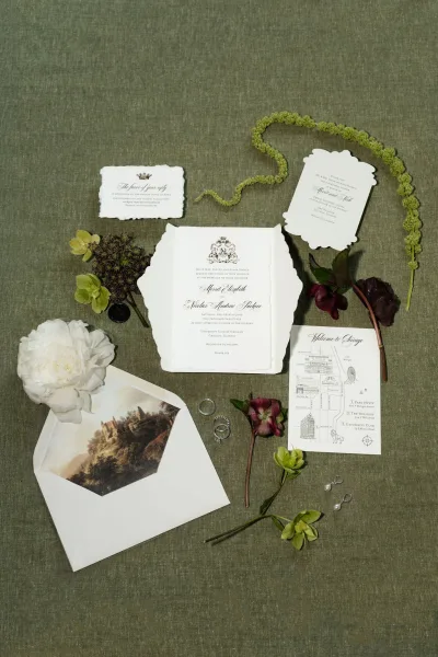 Invitation suite featuring classic wedding invitations with a wax seal, arranged on green linen fabric for an elegant, timeless look.