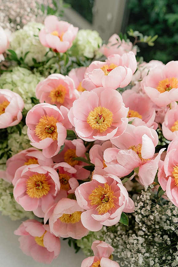 Wedding bouquet with a pink peony bouquet look, featuring white hydrangea, baby's breath, and greenery on a neutral surface