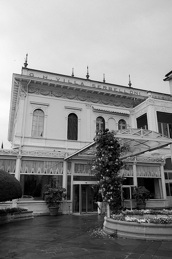 Wedding venue exterior of a historic wedding venue with awning canopy, balcony railing, shutters, and potted plants along the courtyard facade