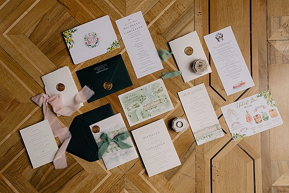Wedding invitation suite with wax seal wedding invitations, silk ribbon, envelopes, watercolor cards, and rings on parquet wood floor