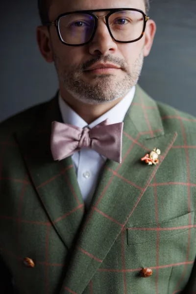 Groom portrait of a groom in a green suit, a lapel pin adding detail to the ensemble for his wedding attire.