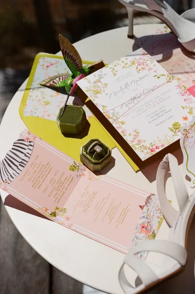 Wedding invitation suite featuring floral wedding invitations arranged with a ring box, styled on a wood deck.