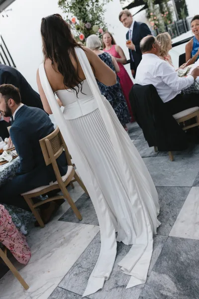 Wedding dress detail shows a strapless wedding dress with a pleated skirt, set among reception dining tables and florals.